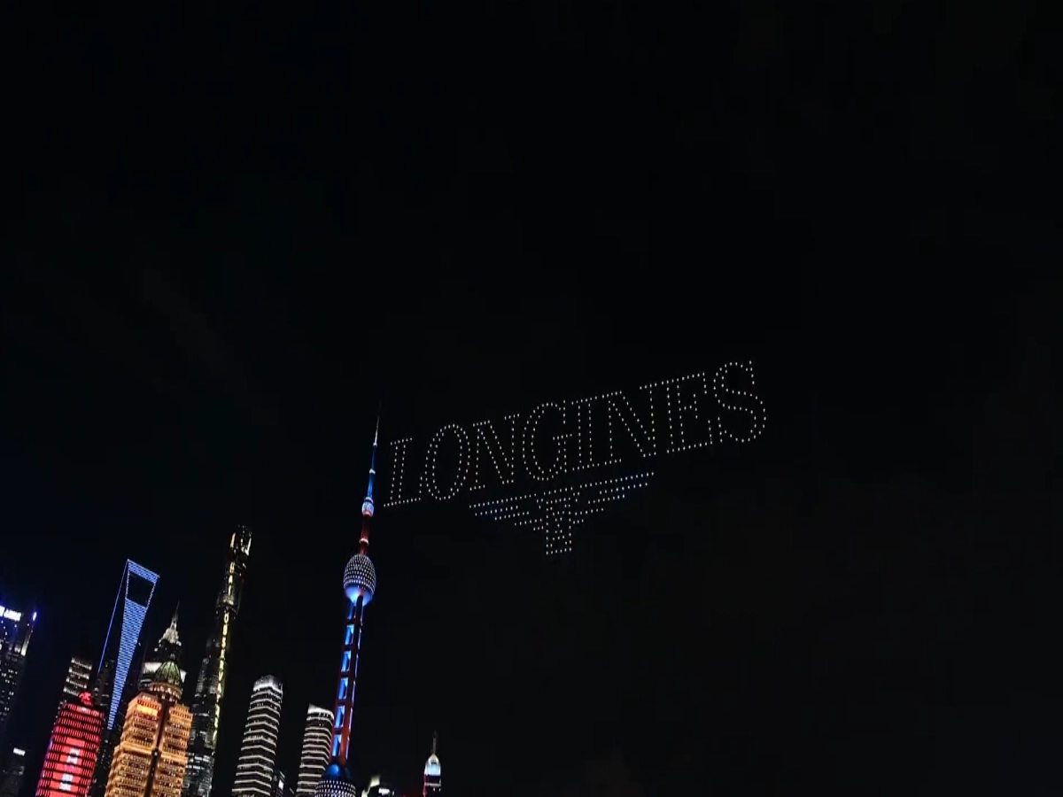 Crostars drones forming Longines brand name in white above Shanghai Bund skyline with Oriental Pearl Tower, 2020