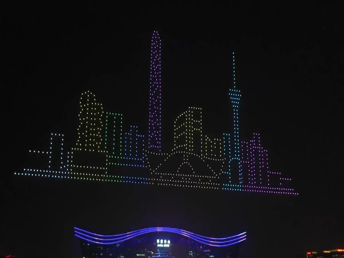 Crostars drone light show night performance, colorful city skyline drone formation above venue building
