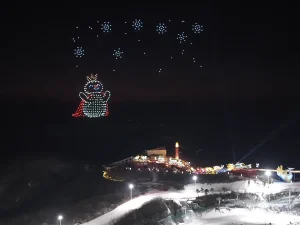 Crostars drones forming cute snowman mascot with snowflakes above Anji ski resort winter night sky, 2026