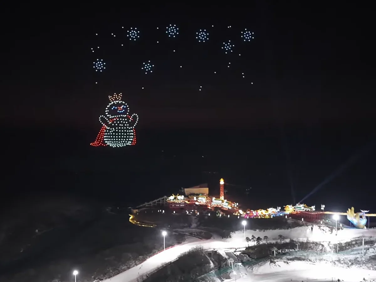 Crostars drones forming cute snowman mascot with snowflakes above Anji ski resort winter night sky, 2026