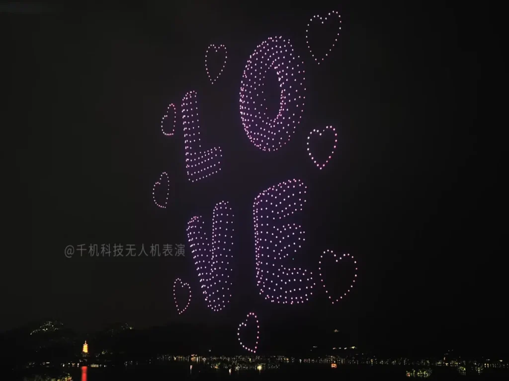 Drones forming the word LOVE with glowing hearts over a lake at night, a romantic drone show formation